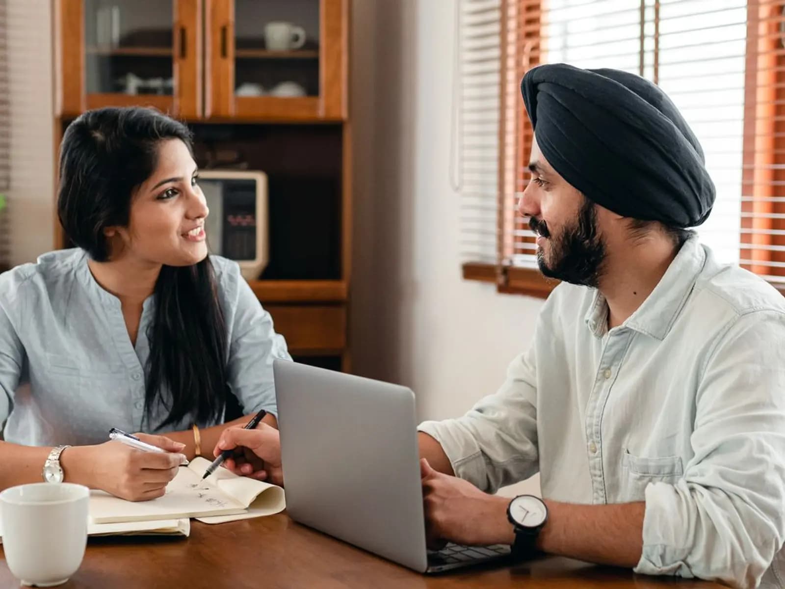 A student and an adviser talking across a desk, notes open beside a laptop.